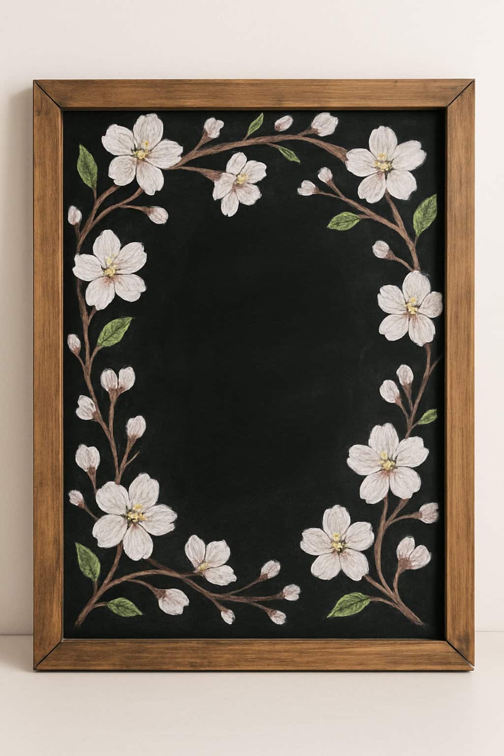 A wood framed chalkboard with decorative blossom-covered branches along the edges and a clean background.