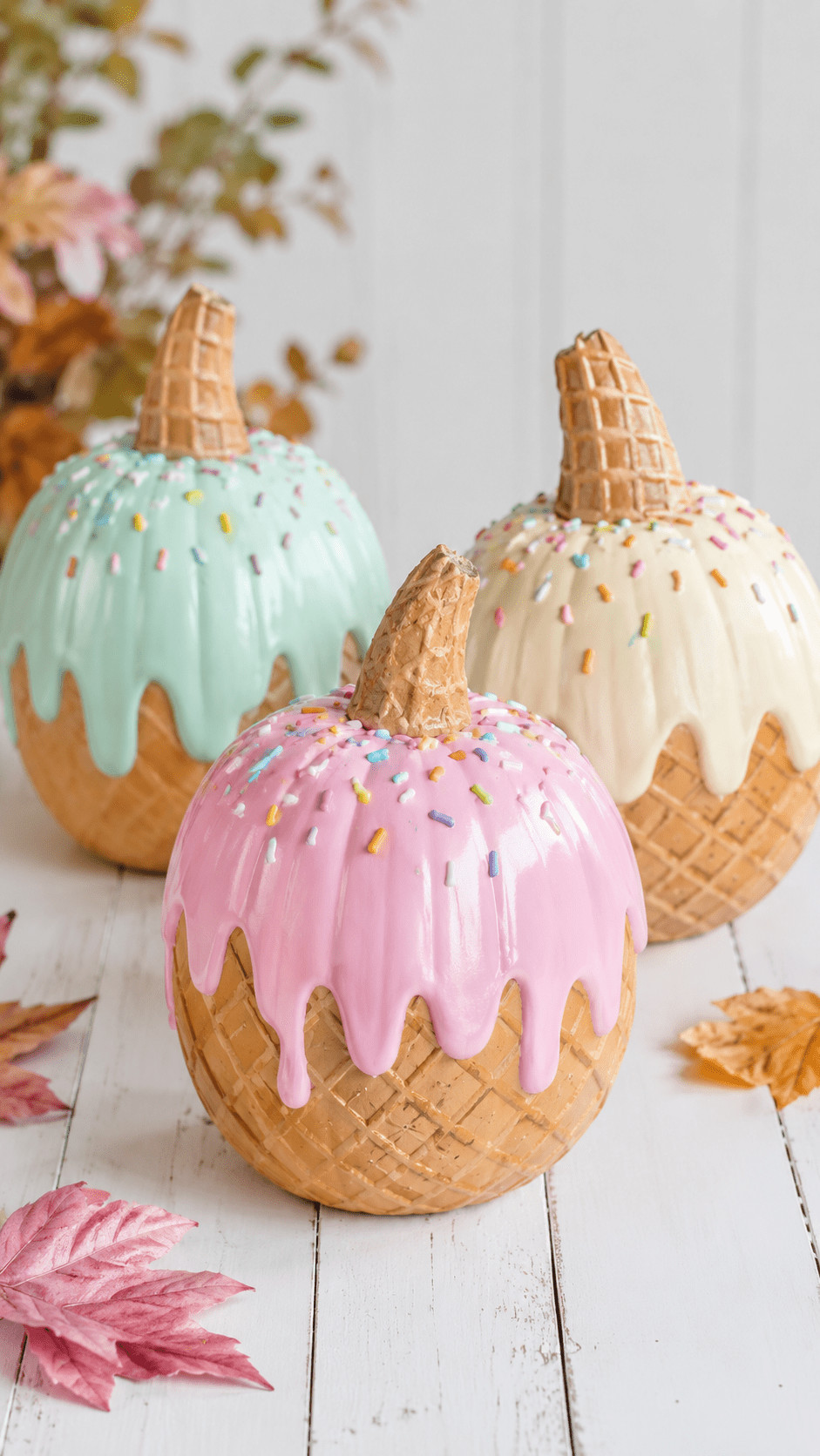 Photo of a pumpkin painted with golden caramel drips and a faux waffle-cone collar, styled on a fall porch with hay bales and gourds.