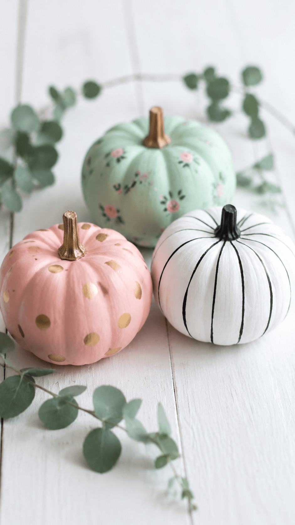 Photo of three mini pumpkins painted in cozy plaid patterns of rust, cream, and forest green on a wooden mantel.