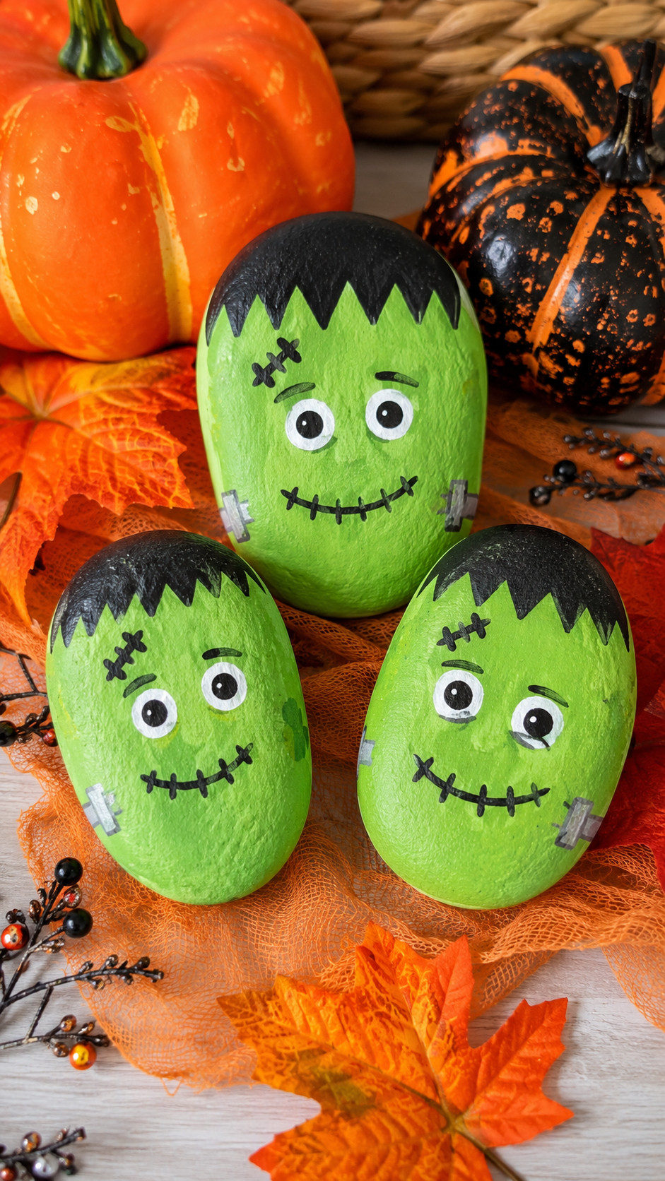 Photo of a midnight-blue and moss-green Frankenstein painted rock with yellow eyes and jagged black hair on a Halloween display.